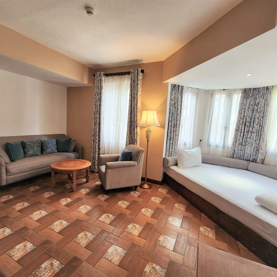 Phòng khách Family Suite: sofa, bàn tròn, giường ngồi bên cửa sổ lồi – Venus Hotel Tam Đảo